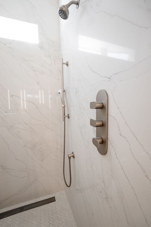 Elegant shower with marble walls and modern fixtures, remodeled by MGD Builders in Phoenix, AZ