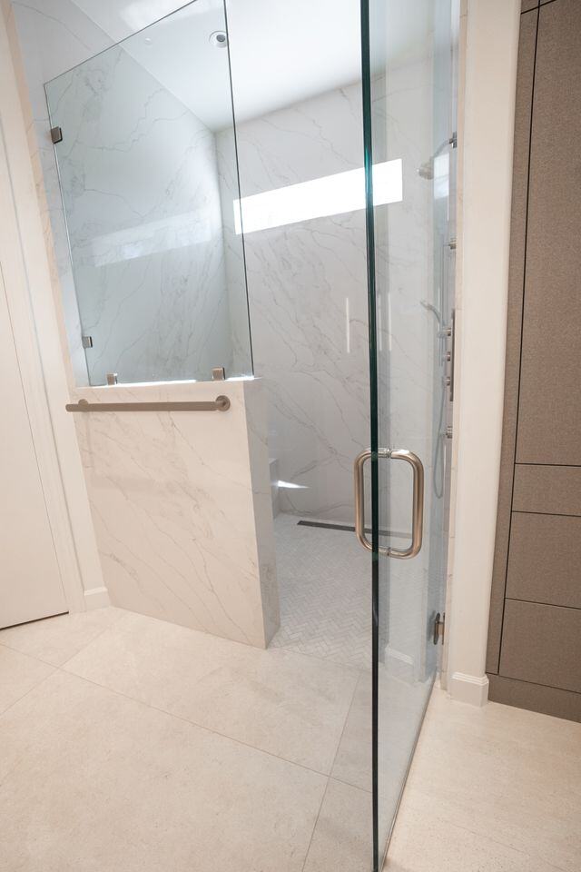 Spacious walk-in shower with marble walls and glass doors, remodeled by MGD Builders in Phoenix, AZ