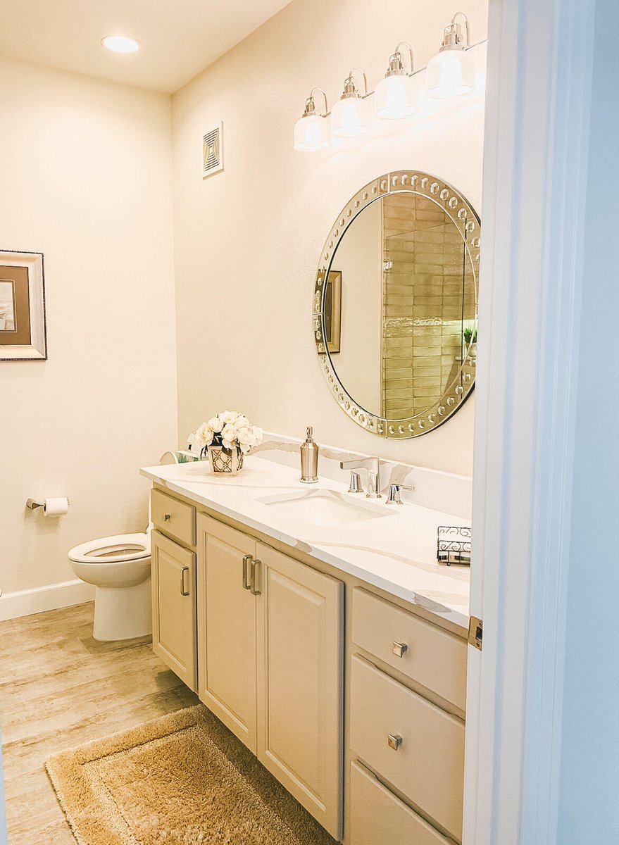 Hall bathroom with a large round mirror and double vanity, remodeled by MGD Builders in Phoenix, AZ