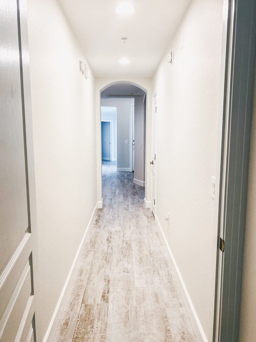 Long hallway with recessed lighting and wood-style flooring, remodeled by MGD Builders in Phoenix, AZ