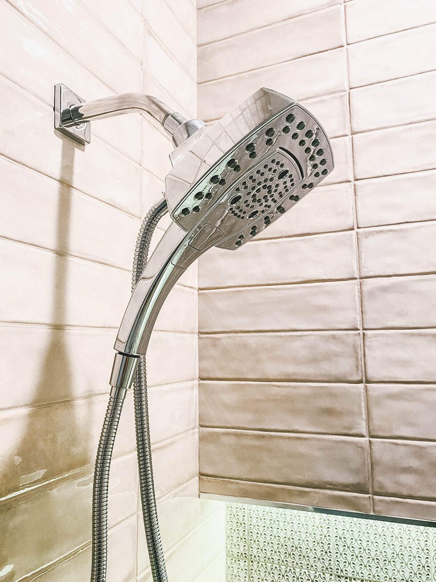 Modern chrome showerhead in a tiled shower, part of a Phoenix, AZ remodel by MGD Builders