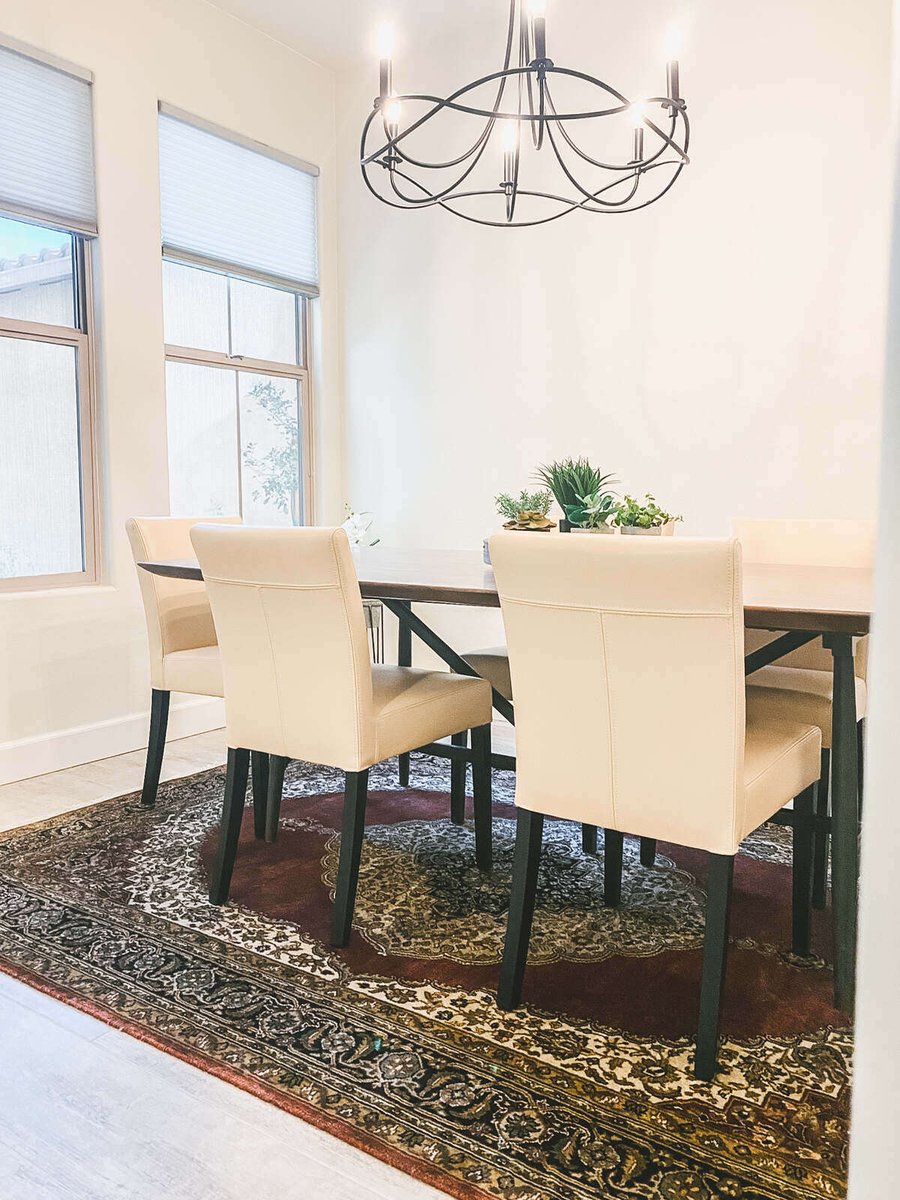 Modern dining room with beige chairs and black chandelier, part of a custom remodel by MGD Builders in Phoenix, AZ