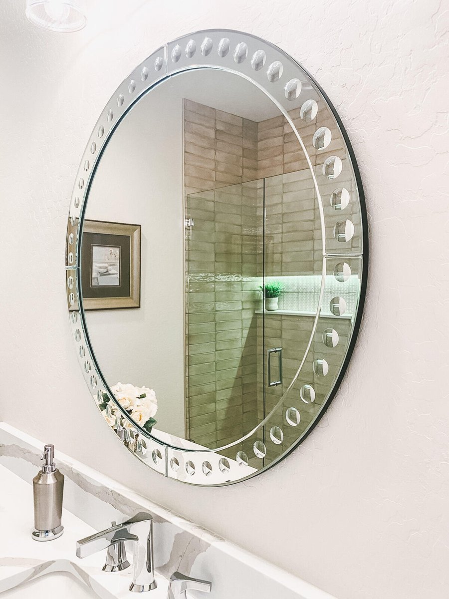 Round bathroom mirror reflecting the shower area in a remodel by MGD Builders in Phoenix, AZ