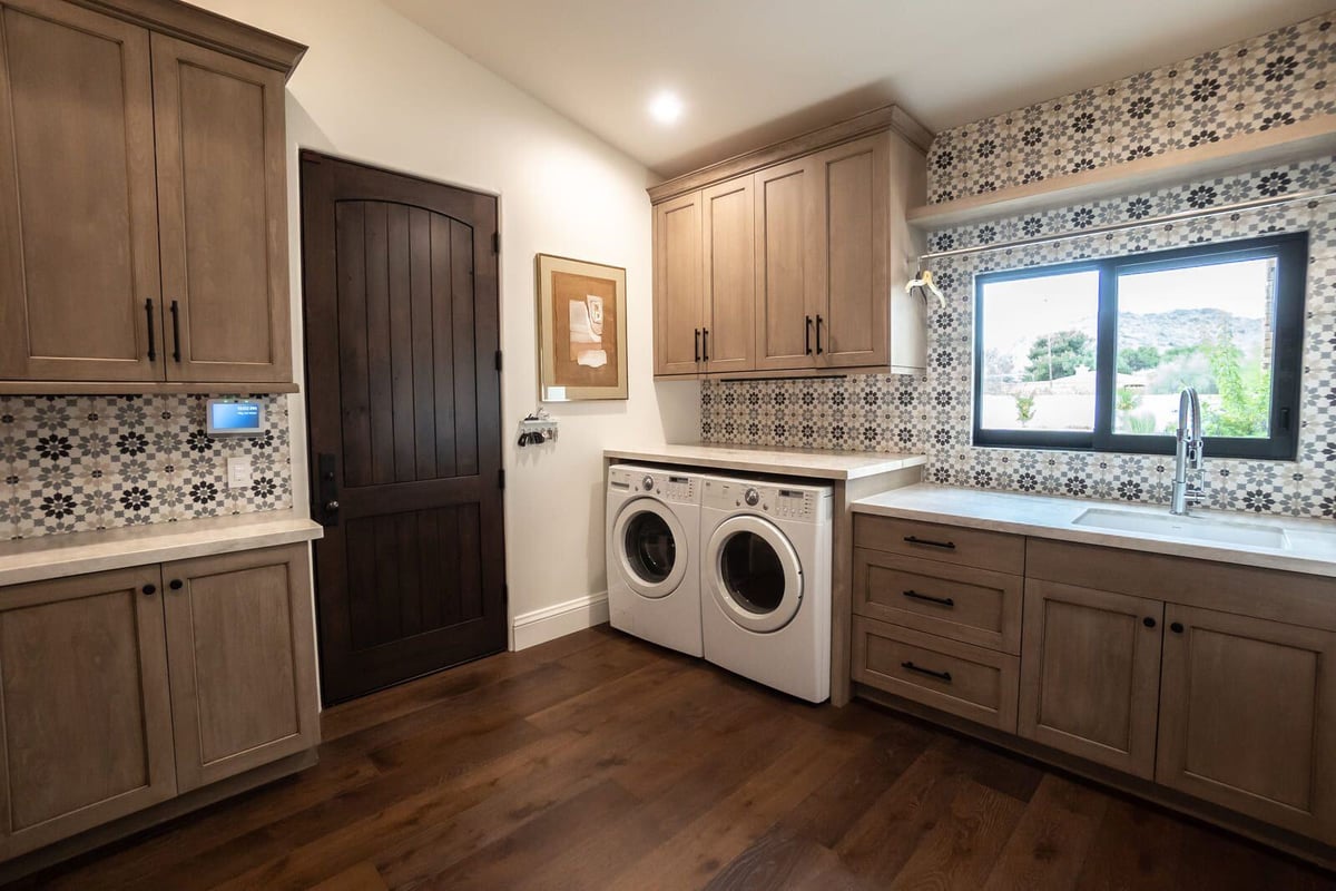 Custom laundry room with wood cabinetry and modern appliances, part of the Mertel Whole Home Renovation by MGD Builders in Phoenix, AZ 